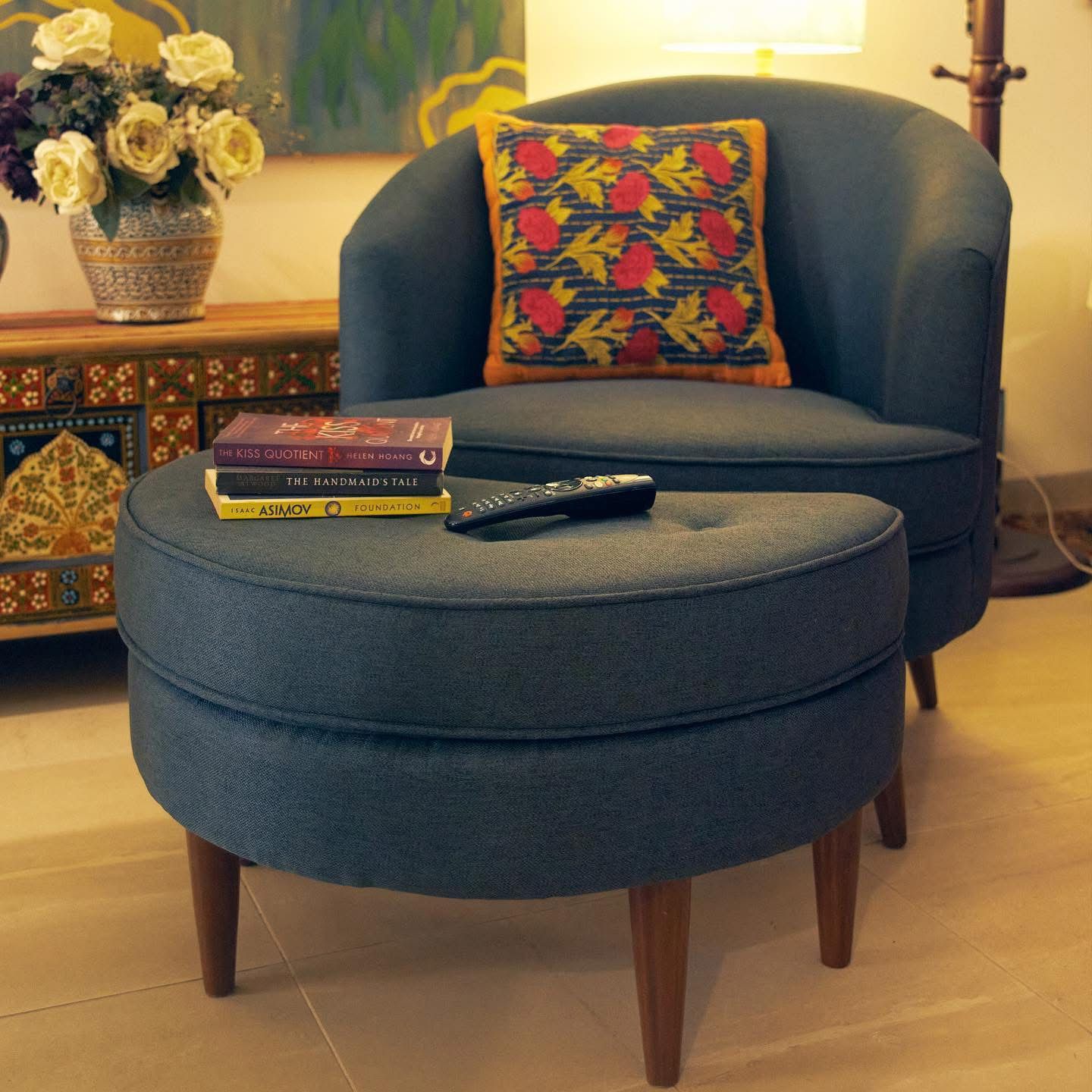 Blue armchair with a patterned pillow and ottoman in a living room setting.